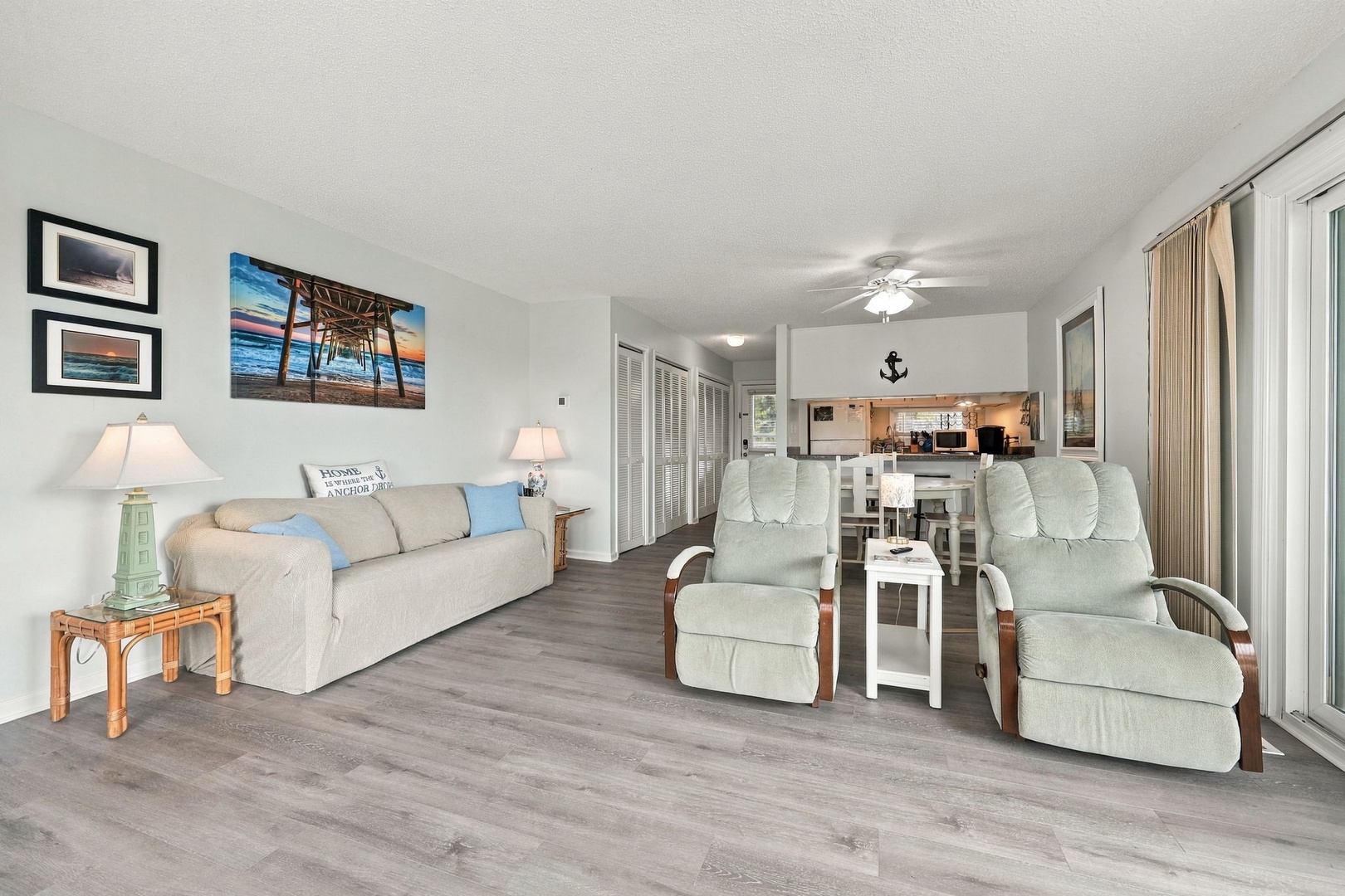 Settle into this bright, beachy living room where coastal charm meets comfort. Recliners and a cozy sofa invite you to relax while cool breezes drift through sliding doors, creating your perfect vacation retreat.