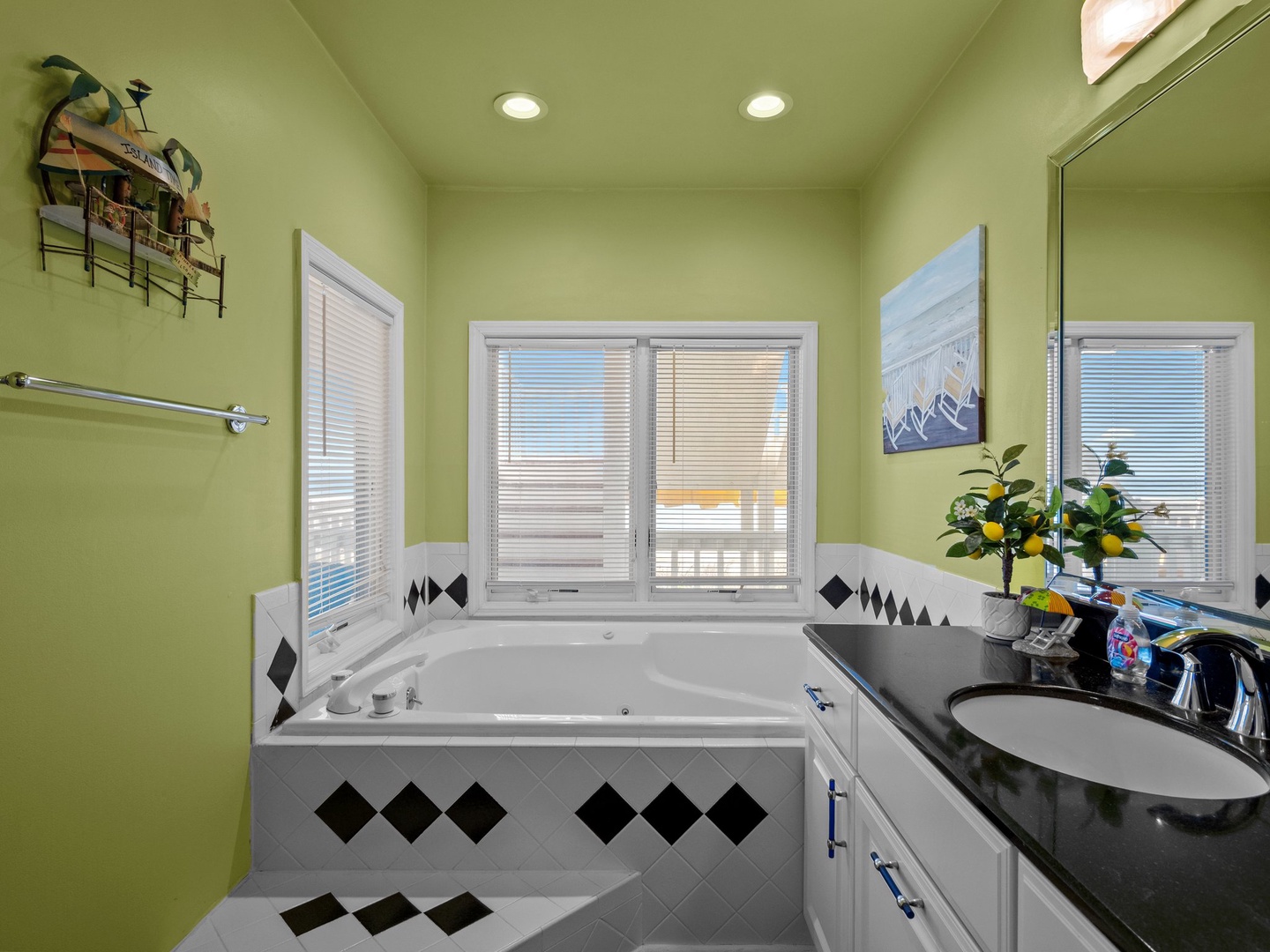 Unwind in your spacious bathroom featuring a deep soaking tub surrounded by windows, where calming green walls create a serene spa-like retreat.