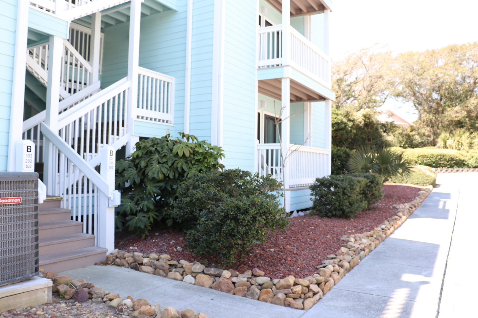 Bright blue coastal apartment building with charming balconies and landscaped grounds creates a welcoming seaside atmosphere.