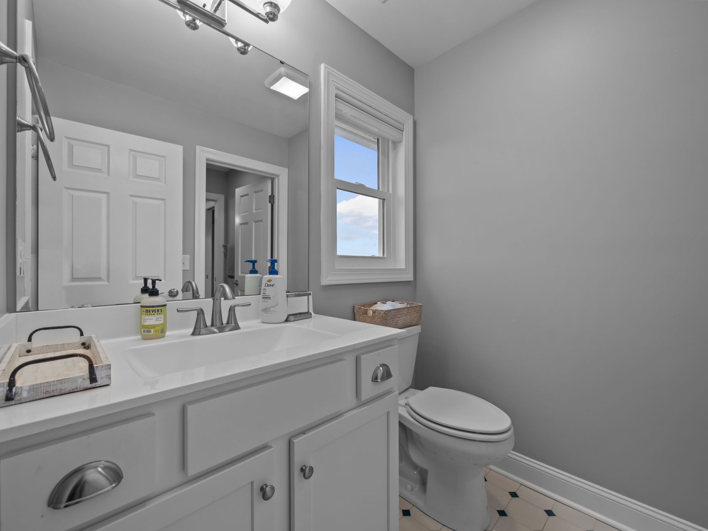 Refresh yourself in this bright, spotless bathroom with modern fixtures and natural light streaming through the window.