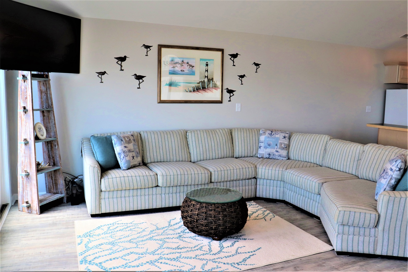 Sink into this cozy sectional with coastal charm. Bird silhouettes dance above striped cushions while your favorite shows play on the mounted TV.