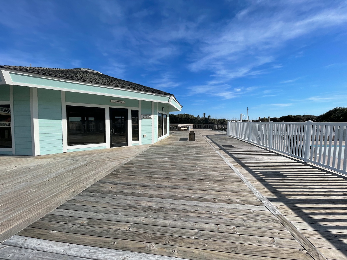 A charming seaside boardwalk leads to local shops and amenities under brilliant blue skies.