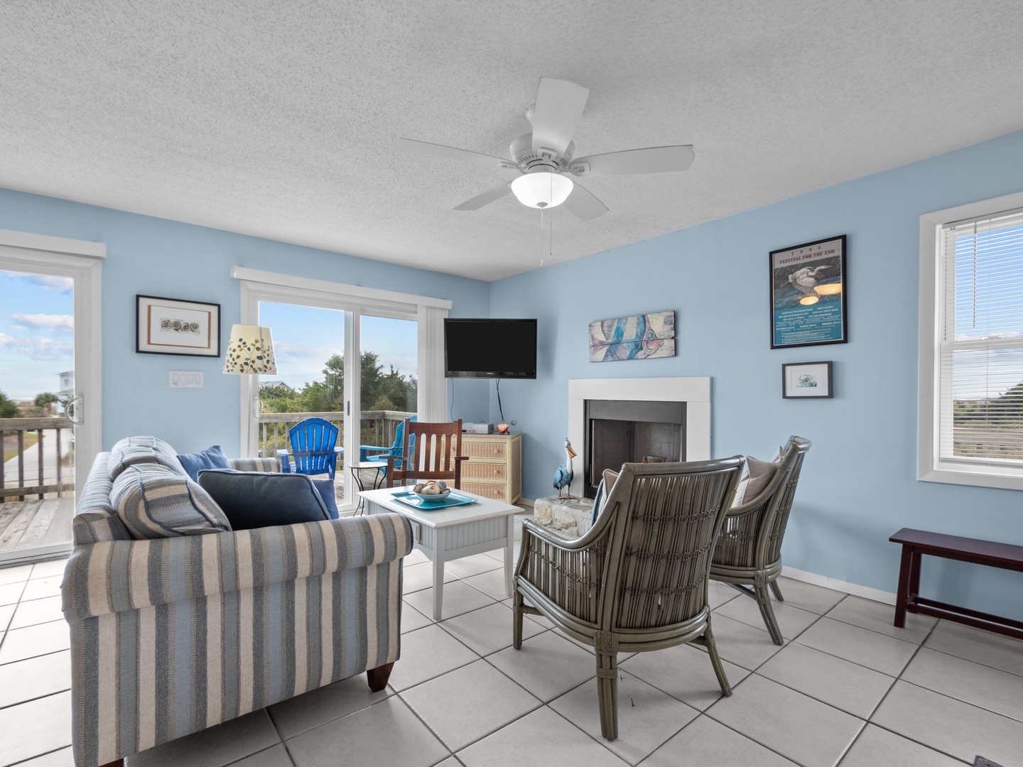 Settle into coastal comfort with soft blues, striped seating, and gentle ceiling fan breezes while enjoying your favorite shows.