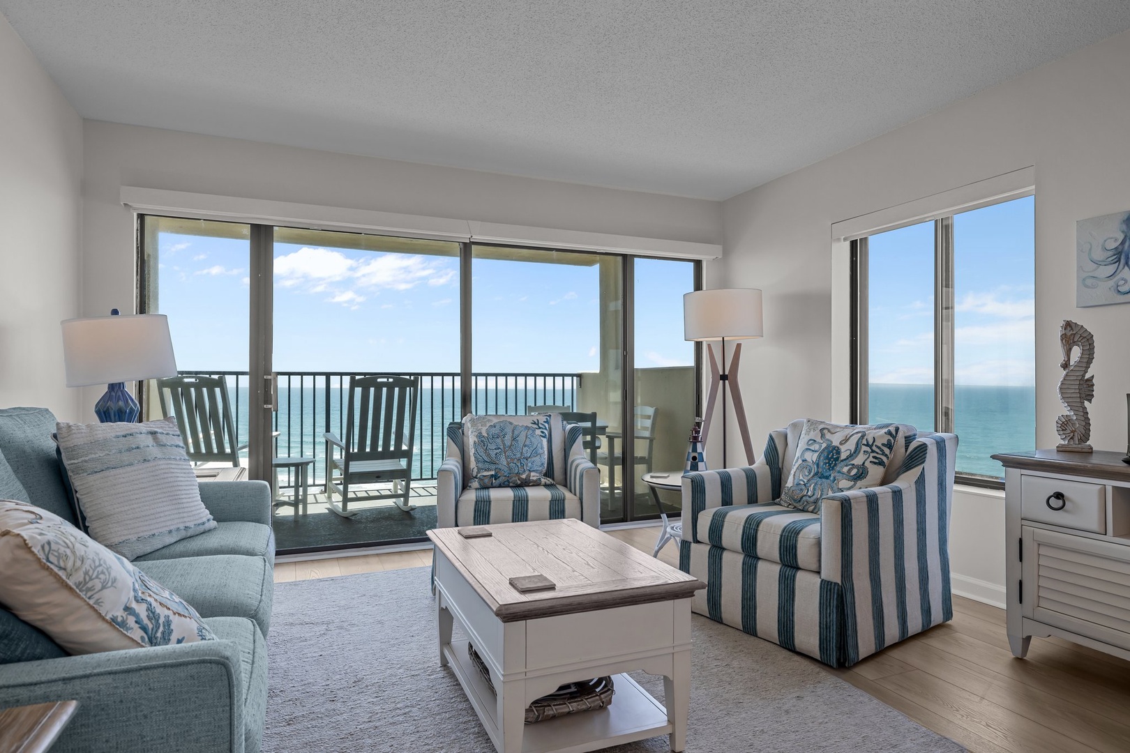 Relax in your coastal living room with stunning ocean views through floor-to-ceiling windows and private balcony access.