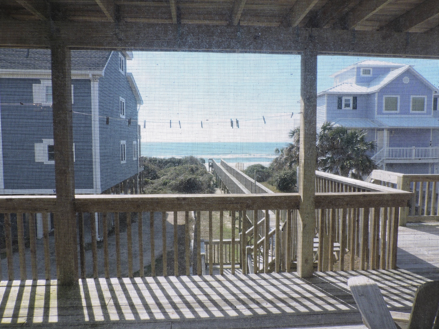 Beachfront balcony with ocean views and direct beach access via wooden walkway through coastal dunes.