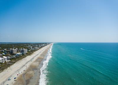 Stunning aerial view showcases pristine coastline with turquoise waters meeting white sandy beach, offering glimpse of the beautiful area surrounding this vacation destination.