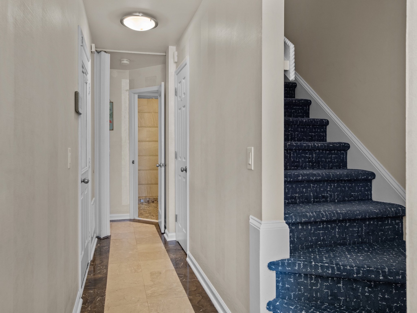 Step into your bright, welcoming hallway with fresh white doors leading to comfortable rooms and stylish blue-speckled stairs to upper levels.