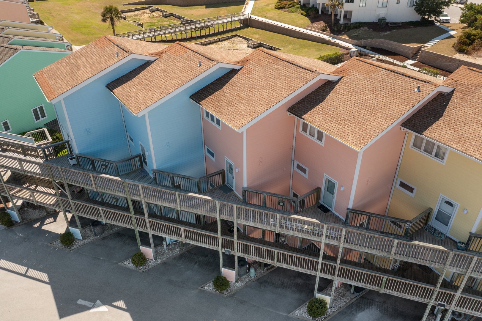 Colorful beachside townhomes with shared boardwalk access and clay tile roofs create a charming coastal community setting.