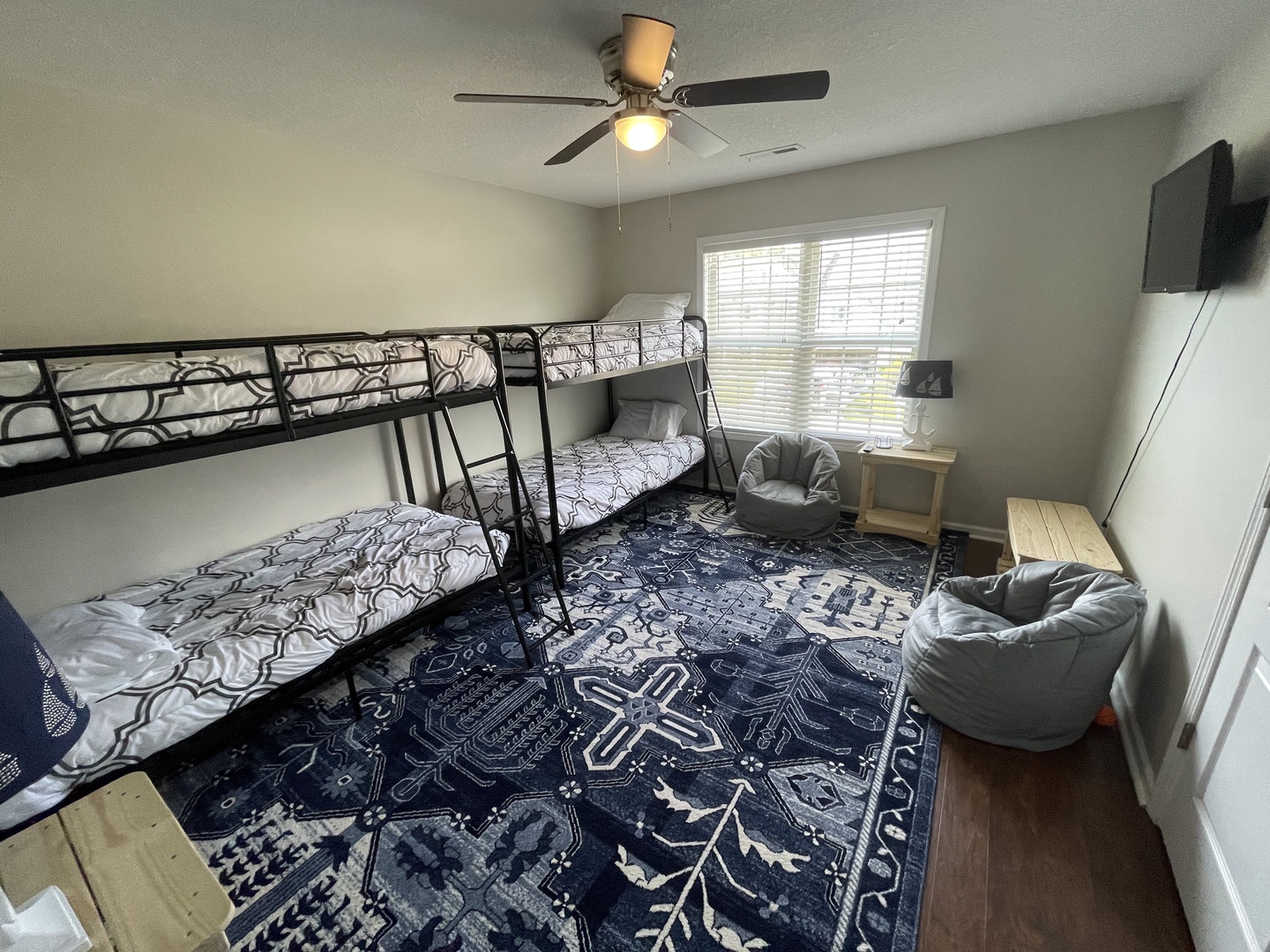 Cozy kids' room with bunk beds, bean bags, and TV for family fun times together.