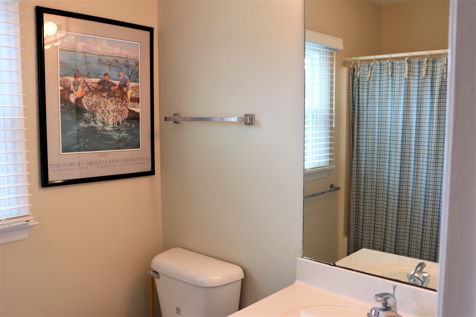 Freshen up in your clean, well-appointed bathroom with modern fixtures and coastal artwork creating a relaxing atmosphere.