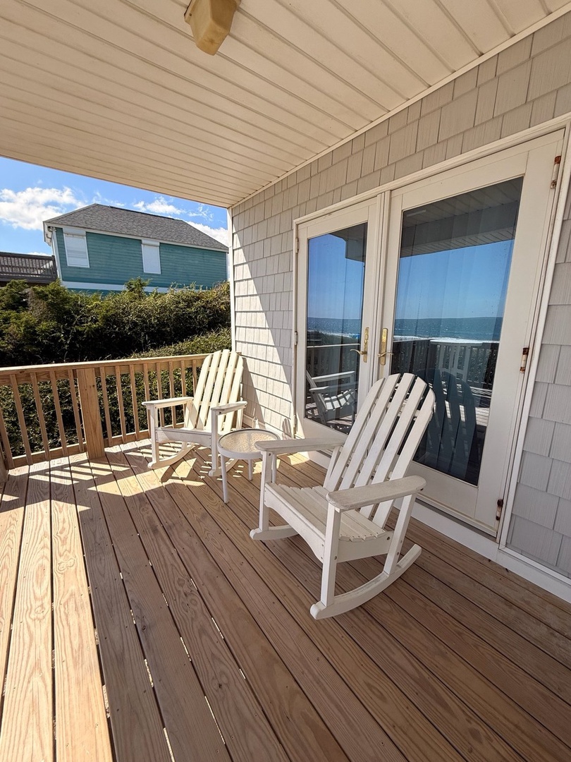 Settle into your rocking chair on this covered deck, where glass doors frame the sparkling ocean just beyond. Perfect for morning coffee or evening breezes with the sound of waves in the background.
