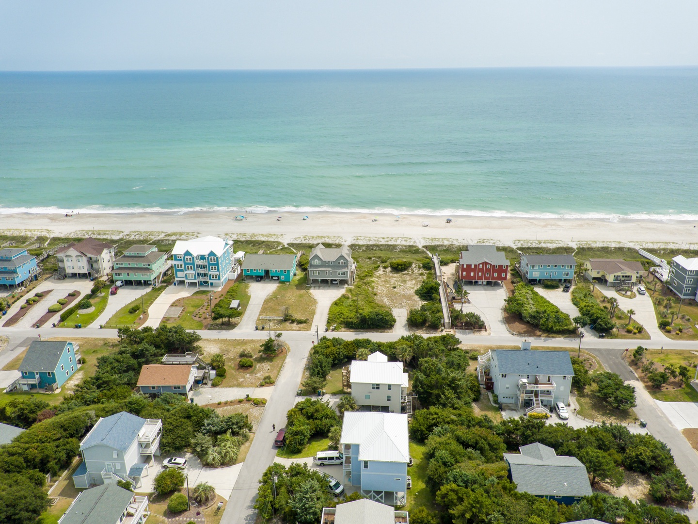 Beachfront vacation rental community featuring colorful coastal homes just steps from pristine sandy shores and turquoise waters.