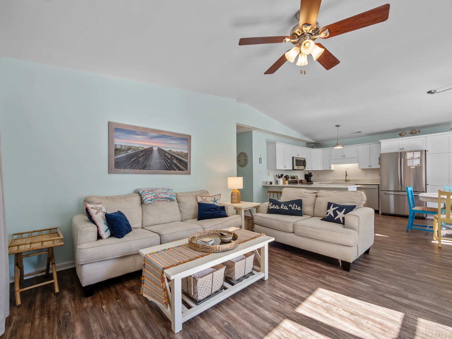 Sink into plush coastal-themed sofas in your open-concept living space, where soothing sea-green walls and beach decor create the perfect retreat.