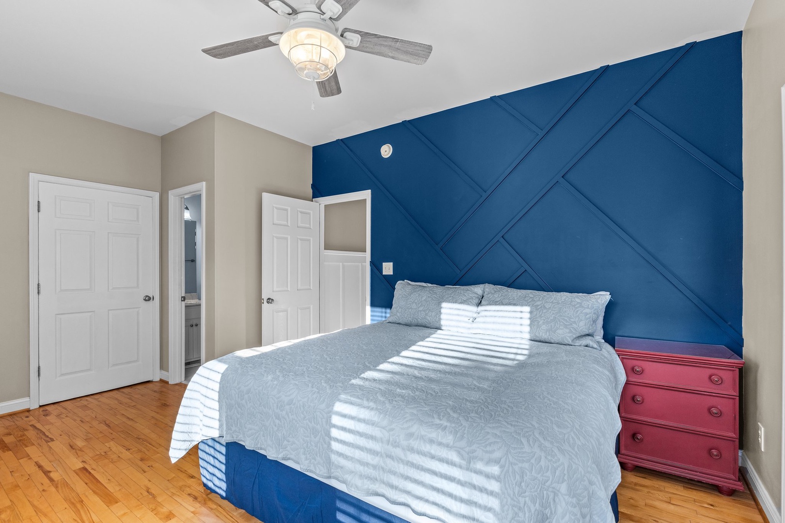 Wake up refreshed in your stylish bedroom with eye-catching navy accent wall, cozy bedding, and natural light streaming through.