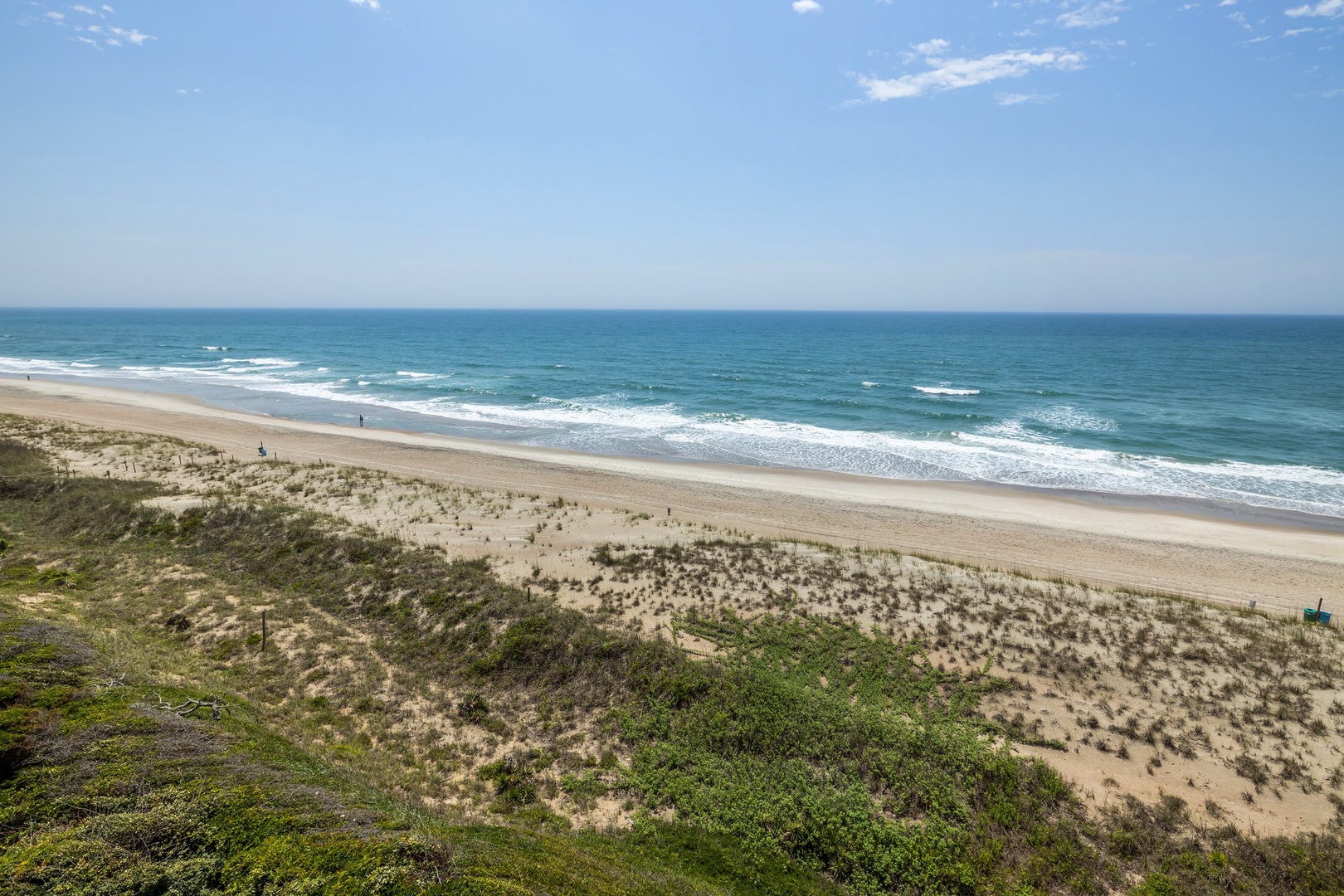 Pristine stretch of coastline with golden sand, rolling waves, and natural dunes creating an unspoiled beachfront setting.
