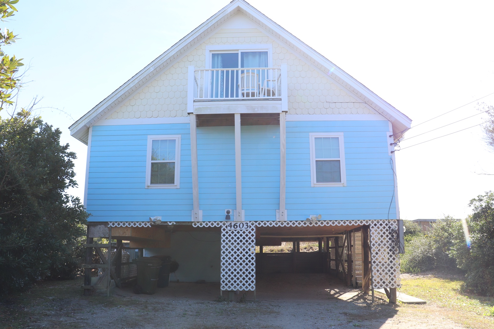 Charming coastal cottage elevated on stilts with a private balcony and covered parking beneath.