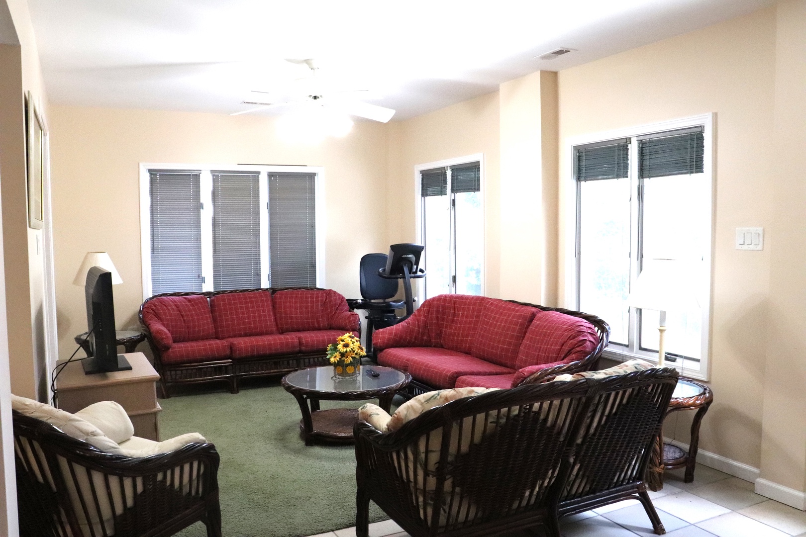 Unwind in your spacious living room featuring comfortable red sofas and wicker chairs, perfect for relaxing after exploring the area.