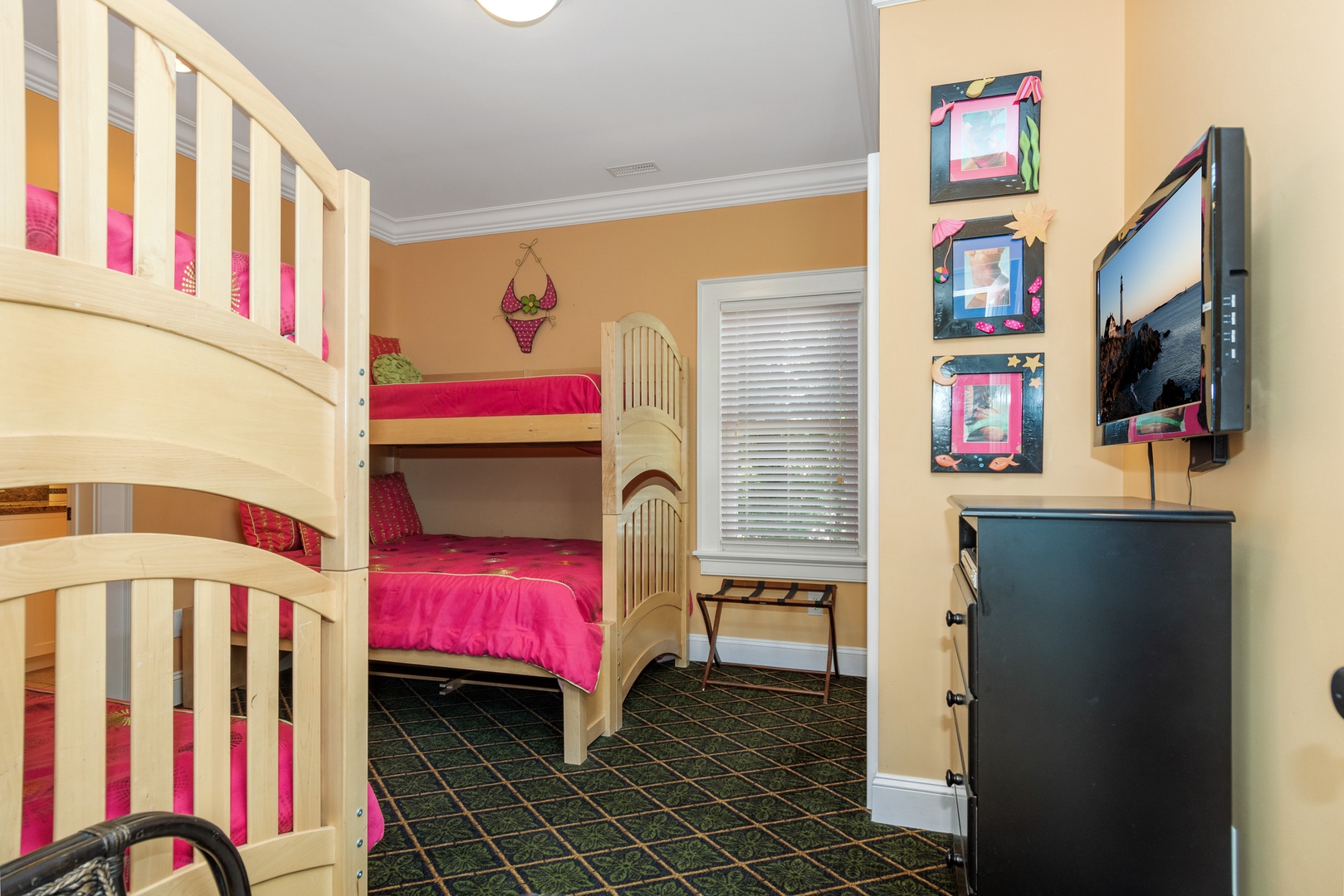 Cozy bunk beds with bright pink bedding create the perfect kids' retreat, complete with TV entertainment for fun-filled stays.