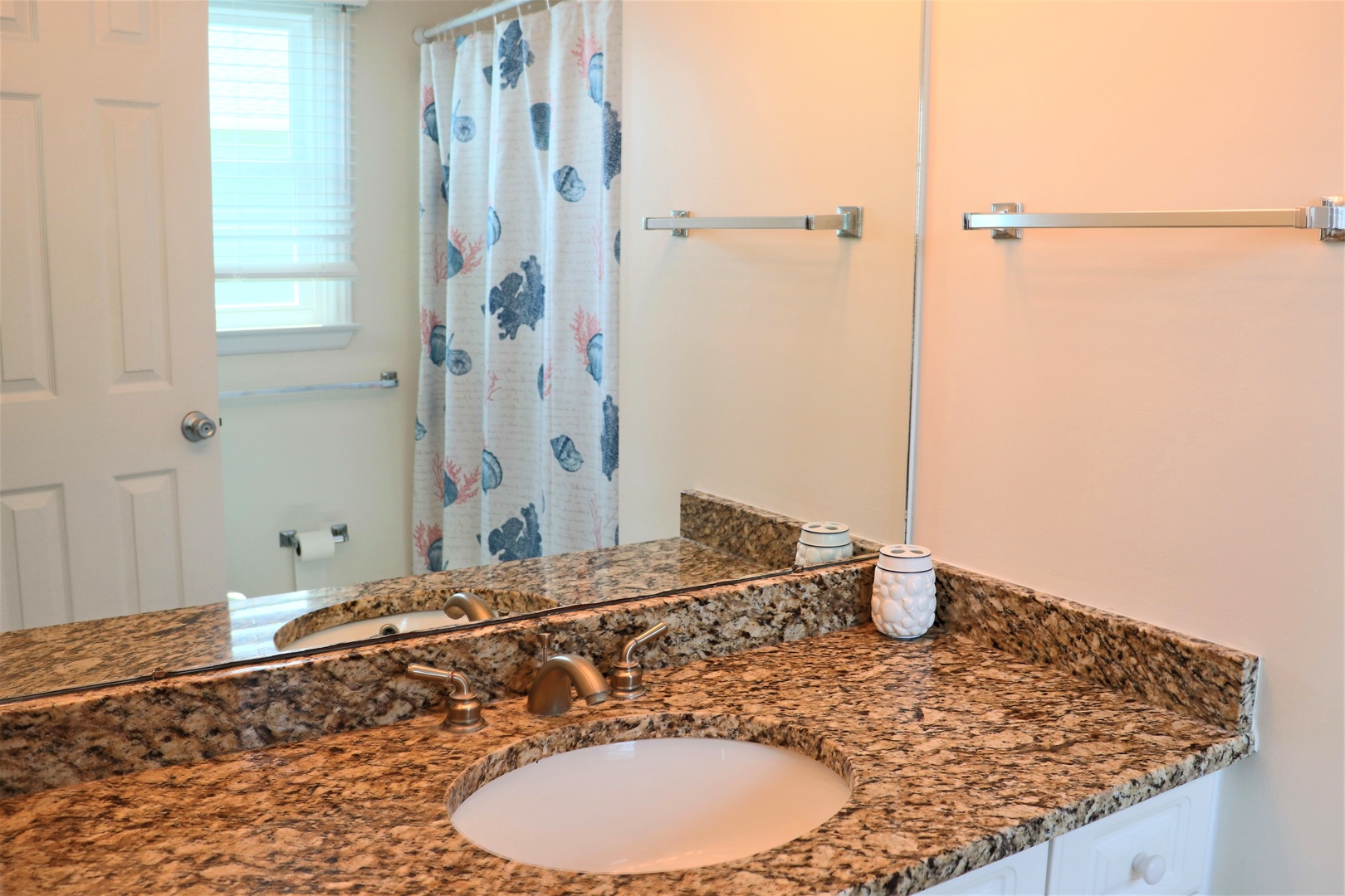 Refresh in your private bathroom featuring granite countertops and a refreshing shower with coastal-themed curtains.