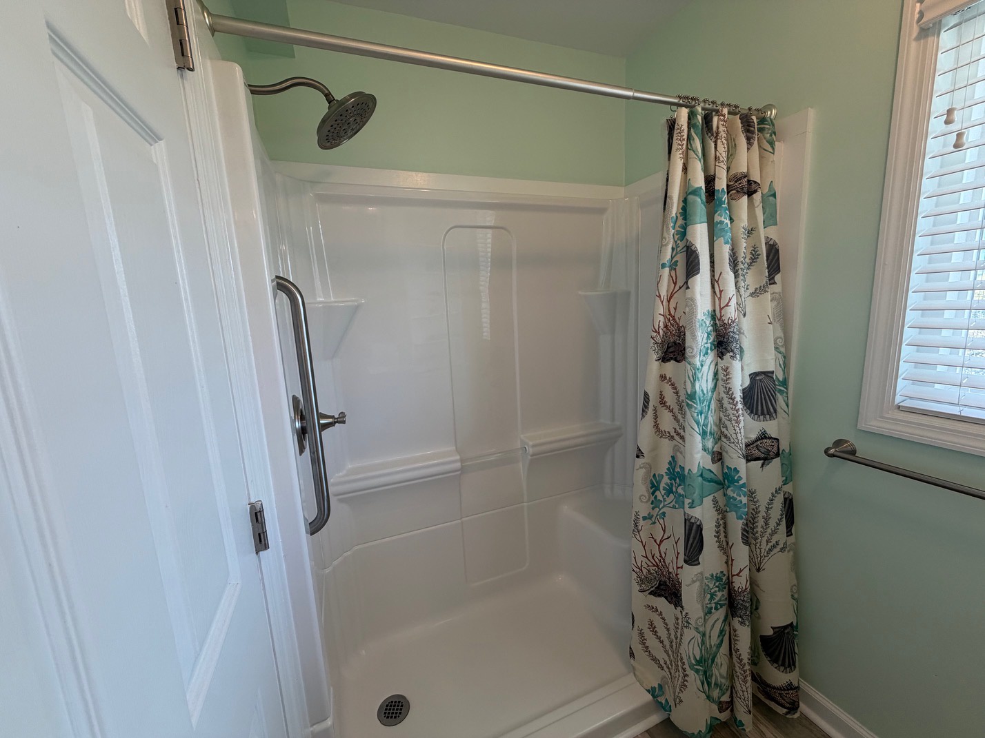 Step into your private shower with coastal-themed curtains and refreshing mint green walls that create a spa-like retreat.