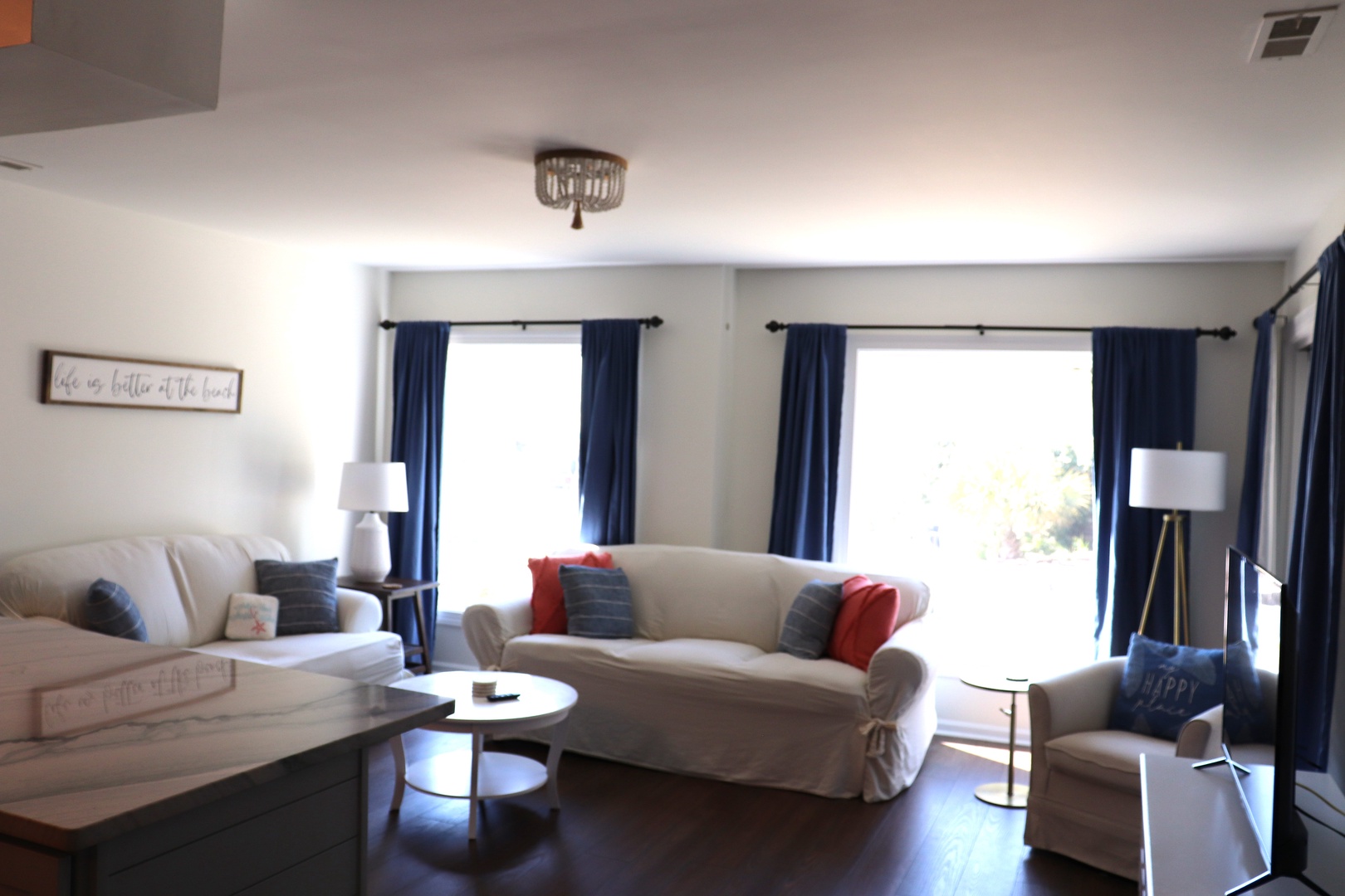 Relax in your bright, airy living room with plush seating, natural light streaming through elegant navy curtains, and thoughtful touches.