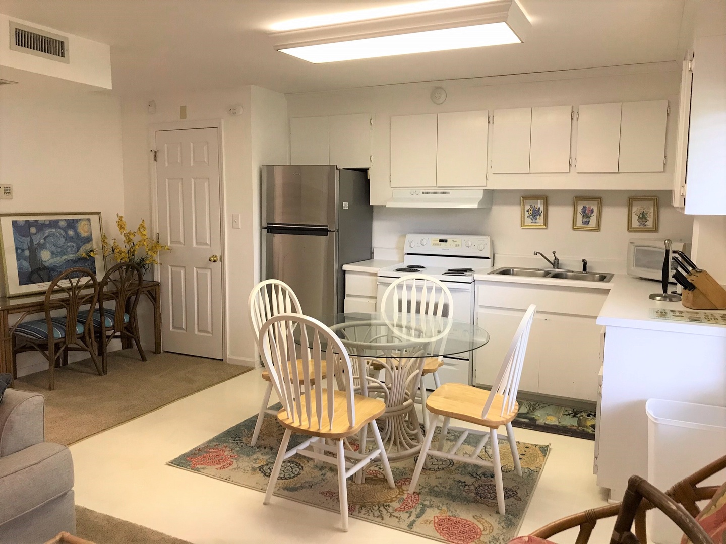 Your bright open kitchen flows seamlessly into the dining area, where you'll enjoy meals at the glass table surrounded by charming white Windsor chairs.