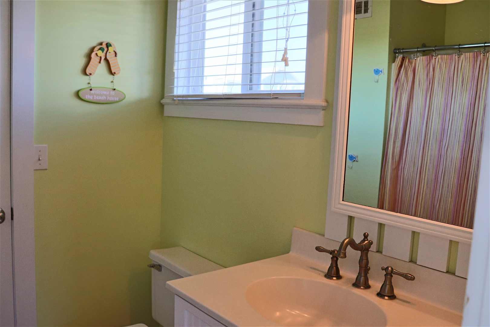 Refresh in your charming beach-themed bathroom with coastal touches and natural light streaming through the window.