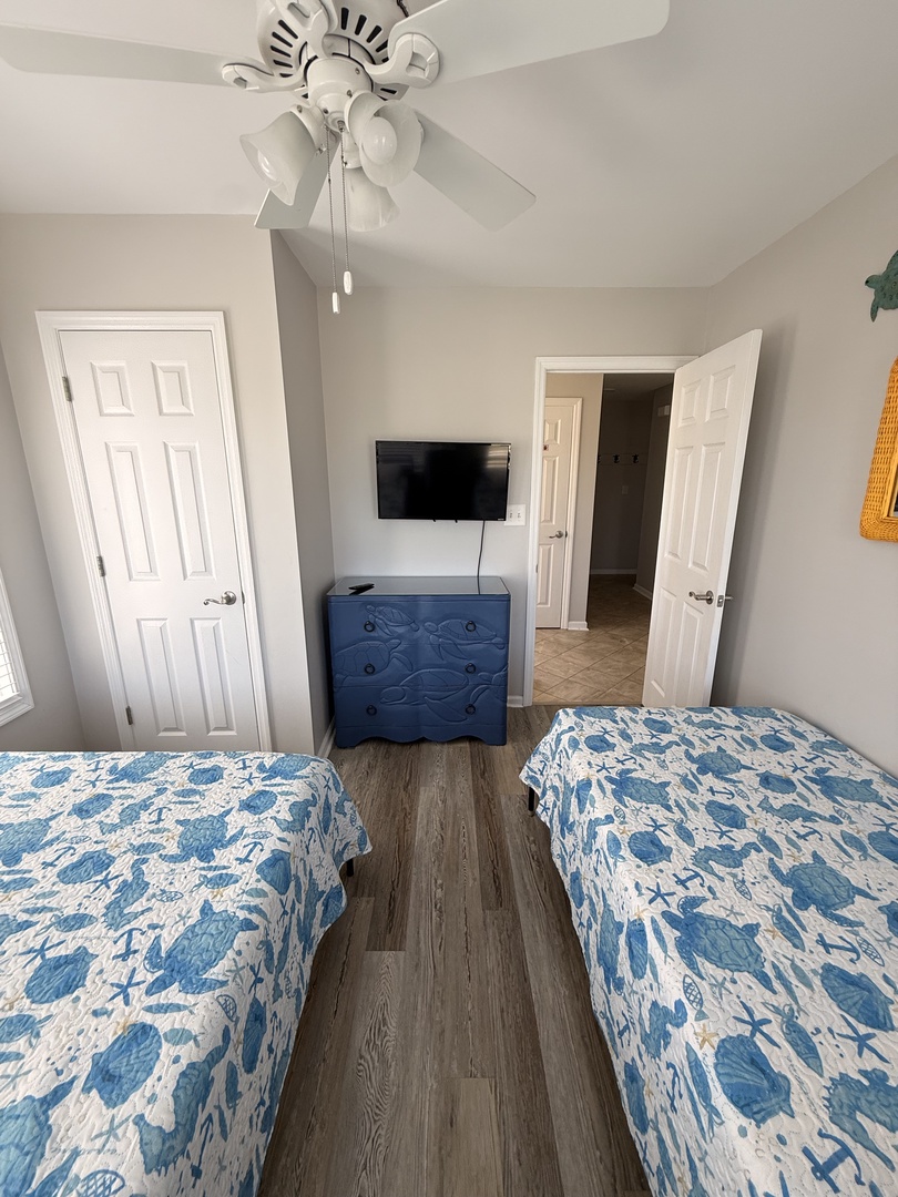Your coastal-inspired bedroom features two comfy beds with ocean-blue quilts, a ceiling fan to keep you cool, and a flat-screen TV for your entertainment. Built-in storage offers plenty of space for your belongings.