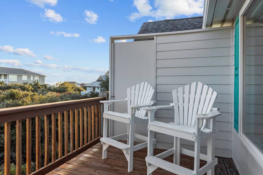 Relax on your private deck with comfortable seating while enjoying views of the neighborhood and blue skies above.