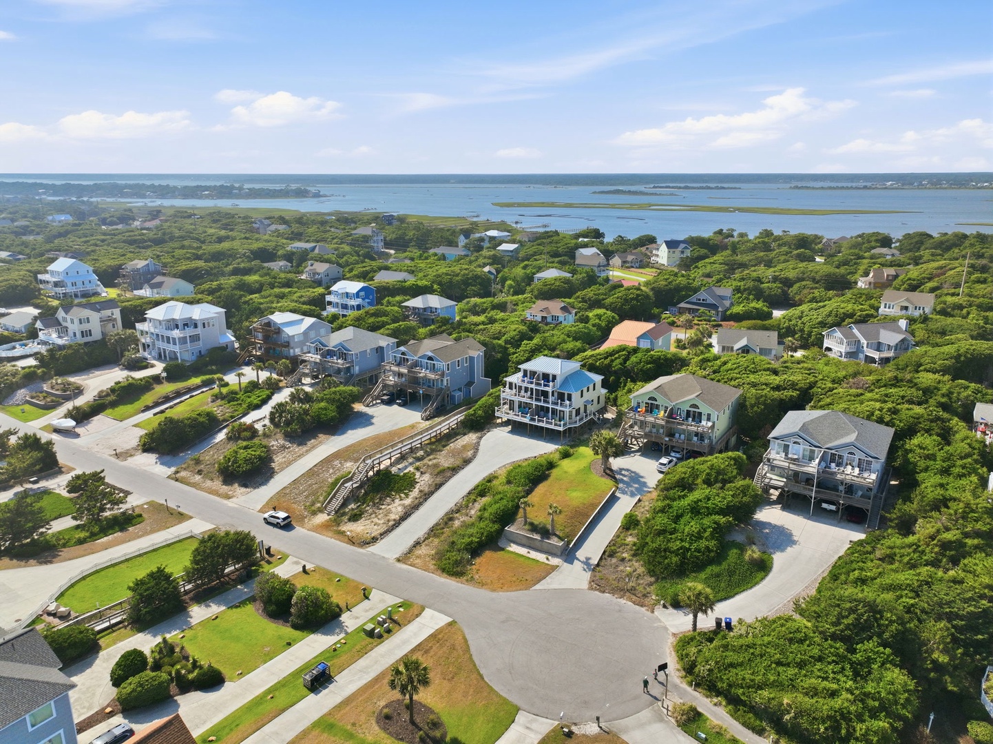 Aerial view of a coastal community featuring the vacation rental property nestled among lush greenery, with serene waterways and islands visible in the distance.