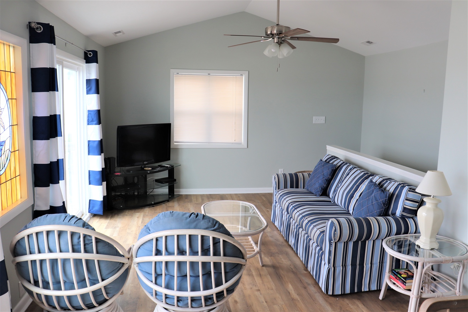 Unwind in your nautical-themed living room with bold striped seating, entertainment center, and coastal charm that feels like home.