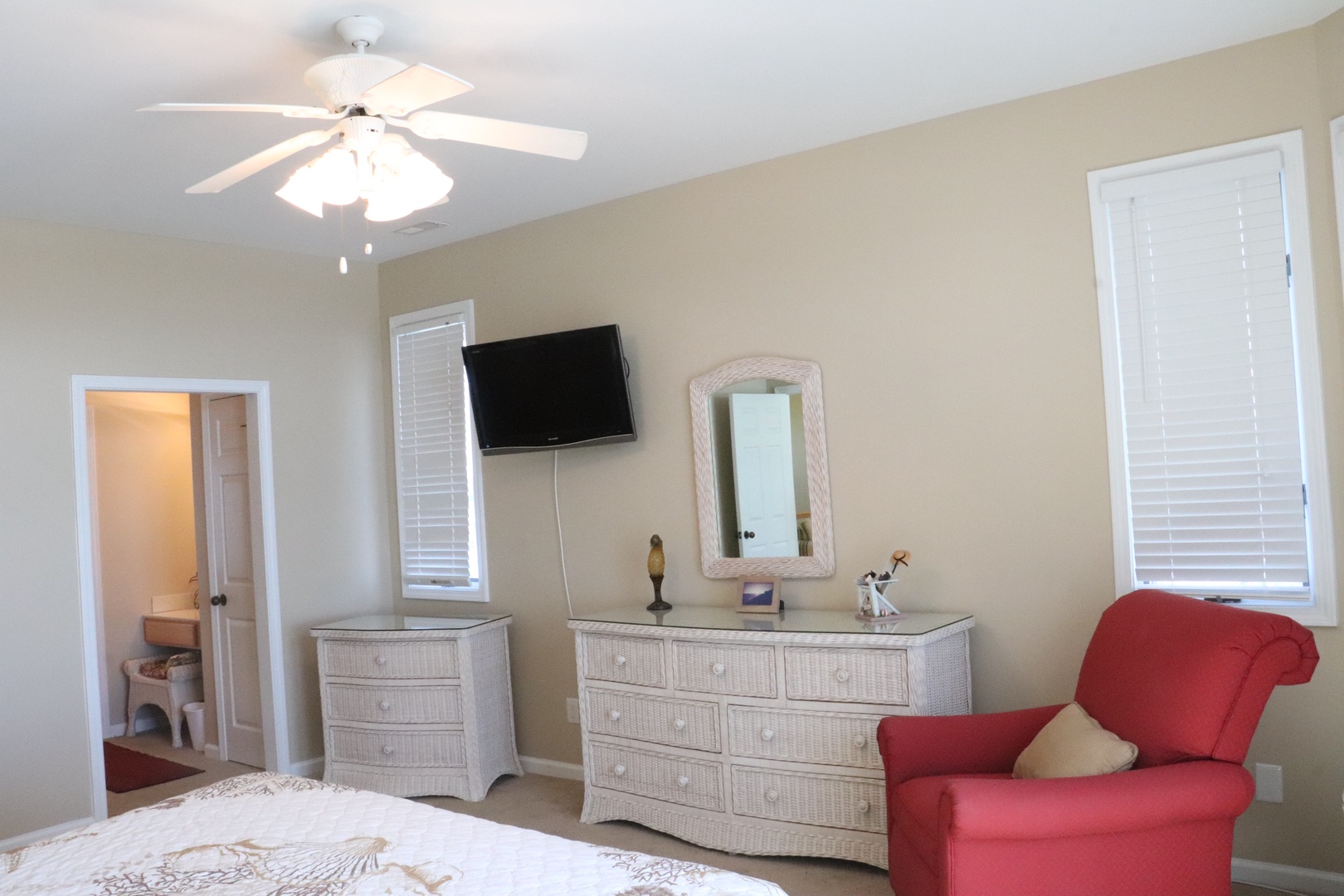 Relax in your spacious bedroom with wall-mounted TV, ceiling fan, and cozy seating area for ultimate comfort.