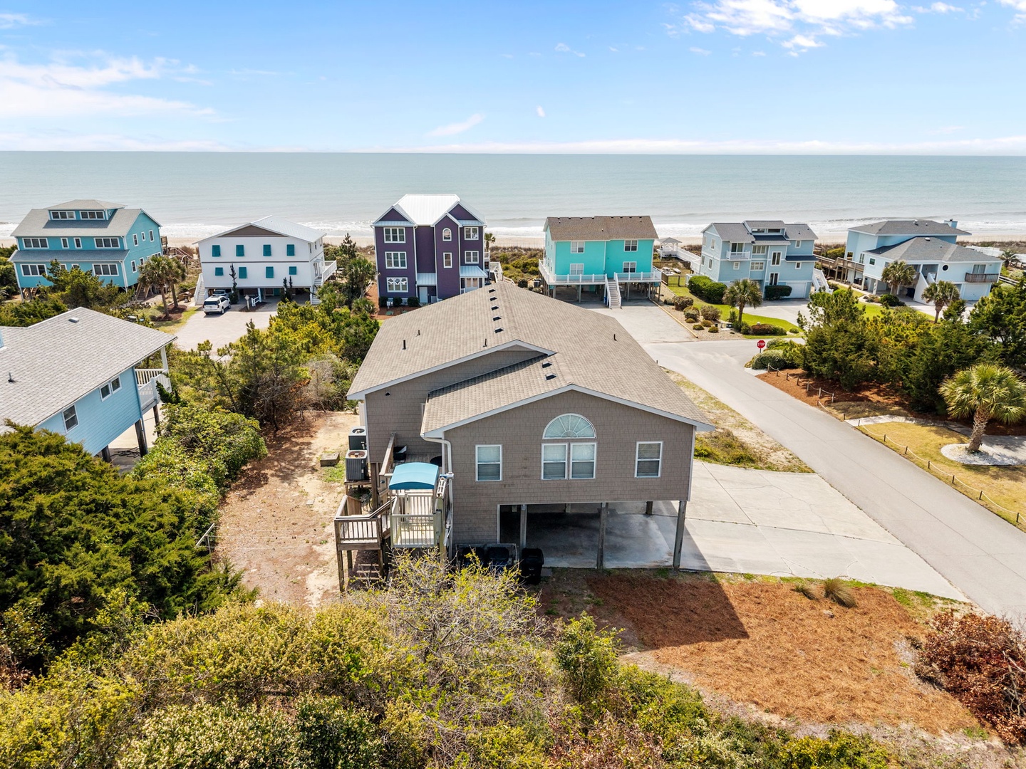 Aerial view of beachfront property nestled among colorful coastal homes with ocean access just steps away.