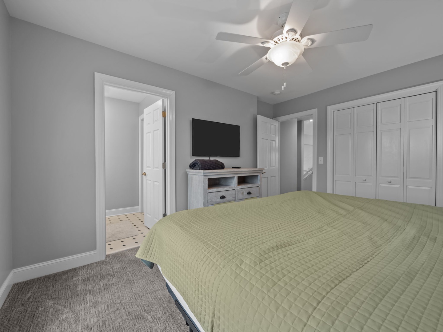 Unwind in your serene bedroom featuring a comfy bed, flat-screen TV, and ceiling fan for perfect climate control.