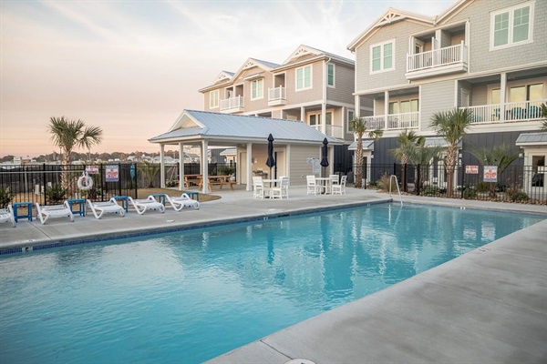 Coastal townhomes overlook this sparkling community pool, where palm trees frame peaceful evening moments.