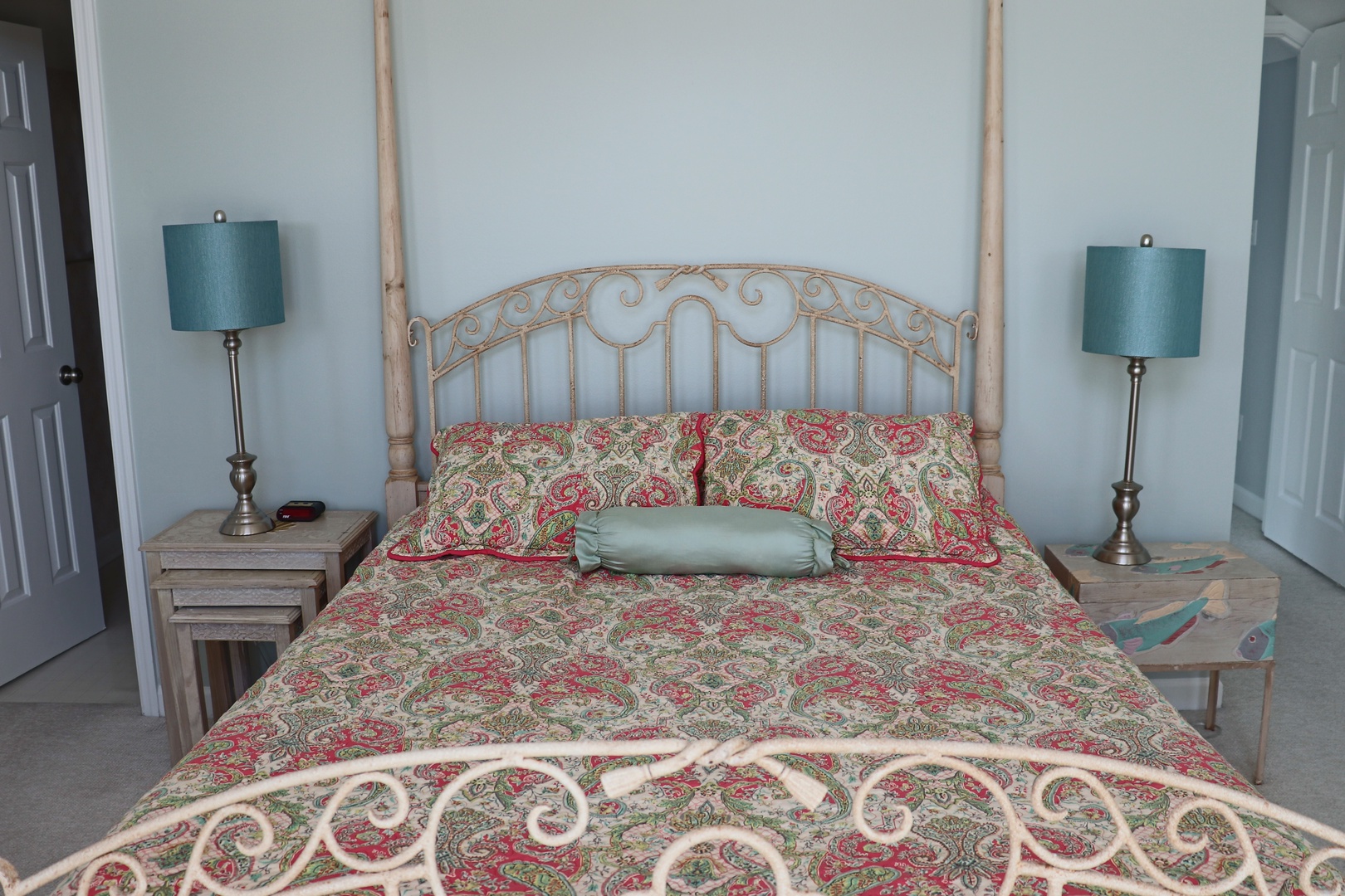 Drift off to peaceful sleep in this elegant bedroom, featuring a beautiful canopy bed with ornate metalwork and charming paisley linens.