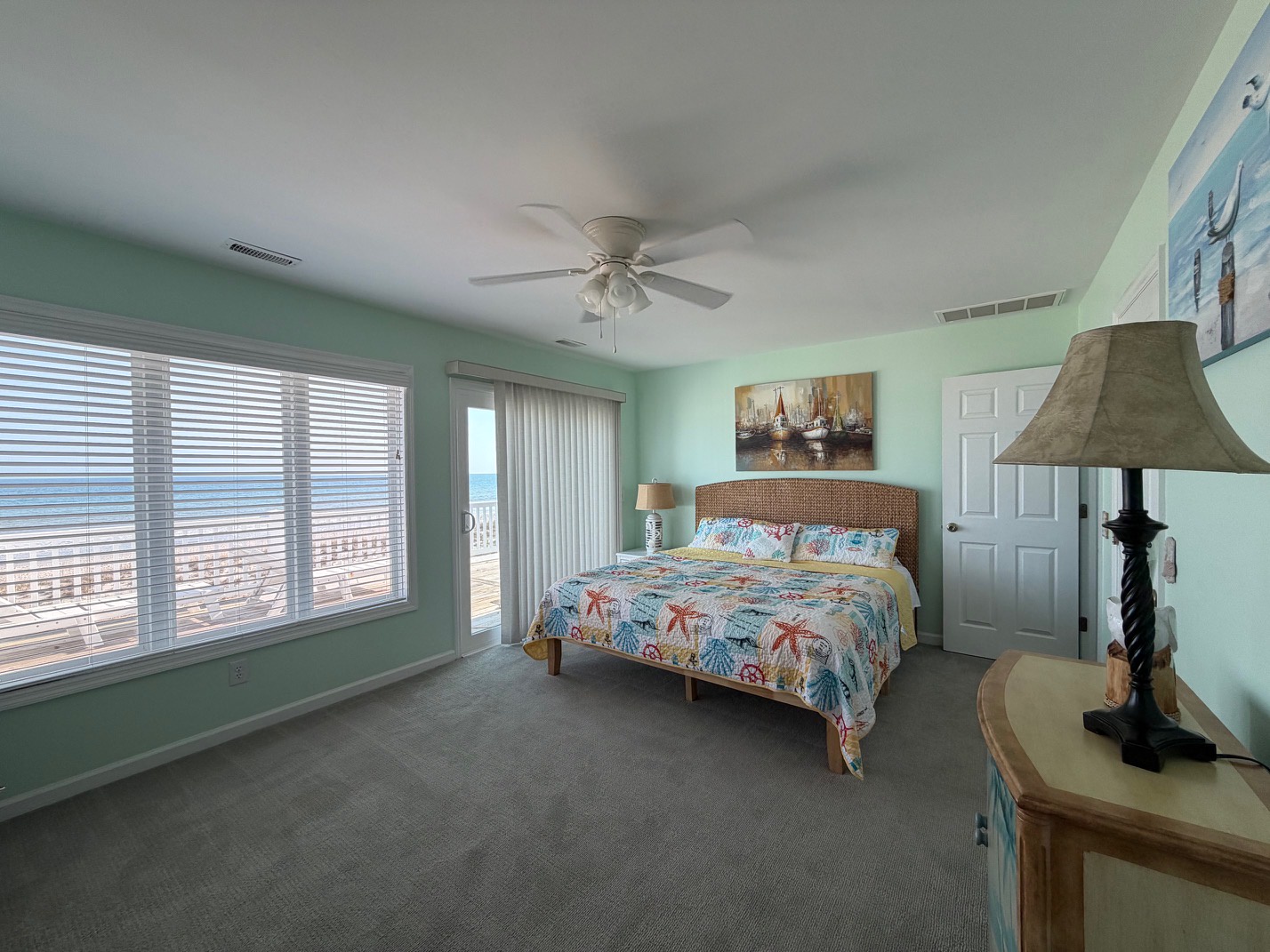 Wake up to coastal views through expansive windows in your serene bedroom, where seafoam walls and nautical touches create the perfect beachside retreat.