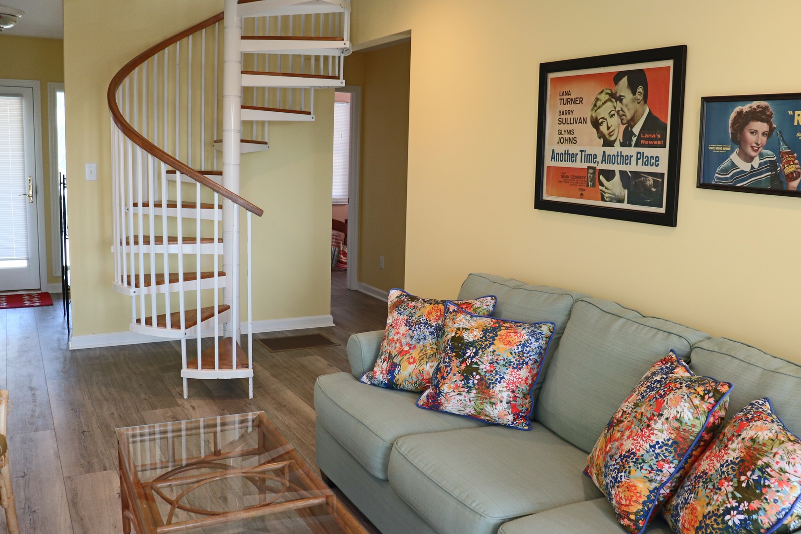 Relax in your stylish living space featuring vintage movie posters, colorful cushions, and a charming spiral staircase leading to private upper levels.