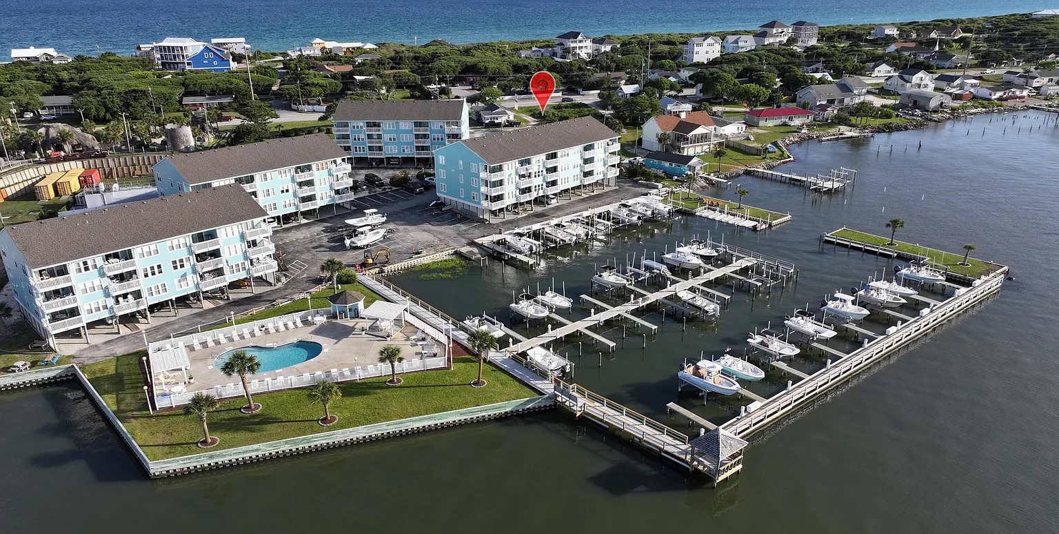Waterfront resort complex with marina, swimming pool, and coastal community surrounded by natural beauty and boat access.