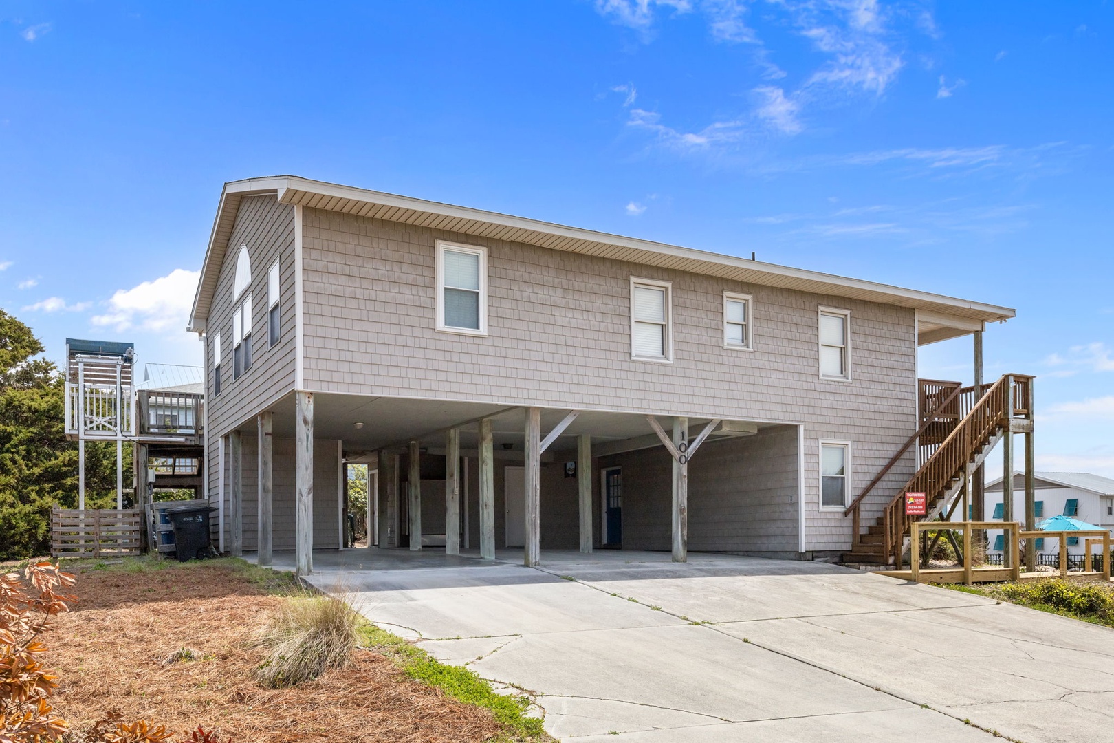Elevated coastal rental with covered parking and easy beach access via wooden stairs.