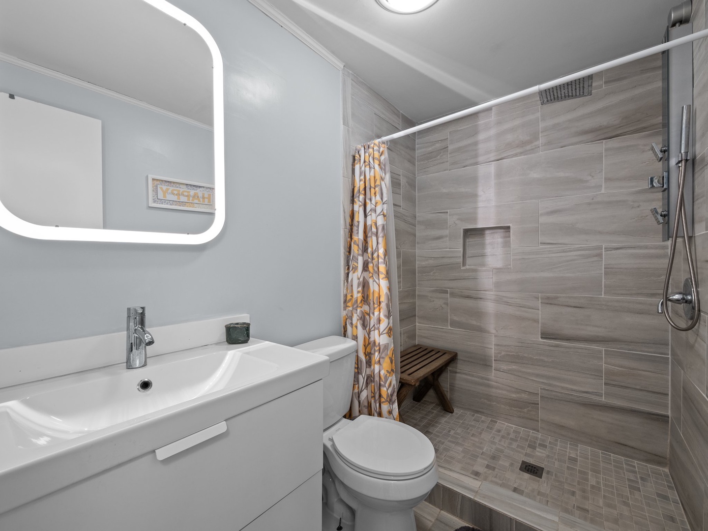 Step into your sleek private bathroom featuring a modern walk-in shower with beautiful wood-grain tiles and thoughtful touches like a shower bench.