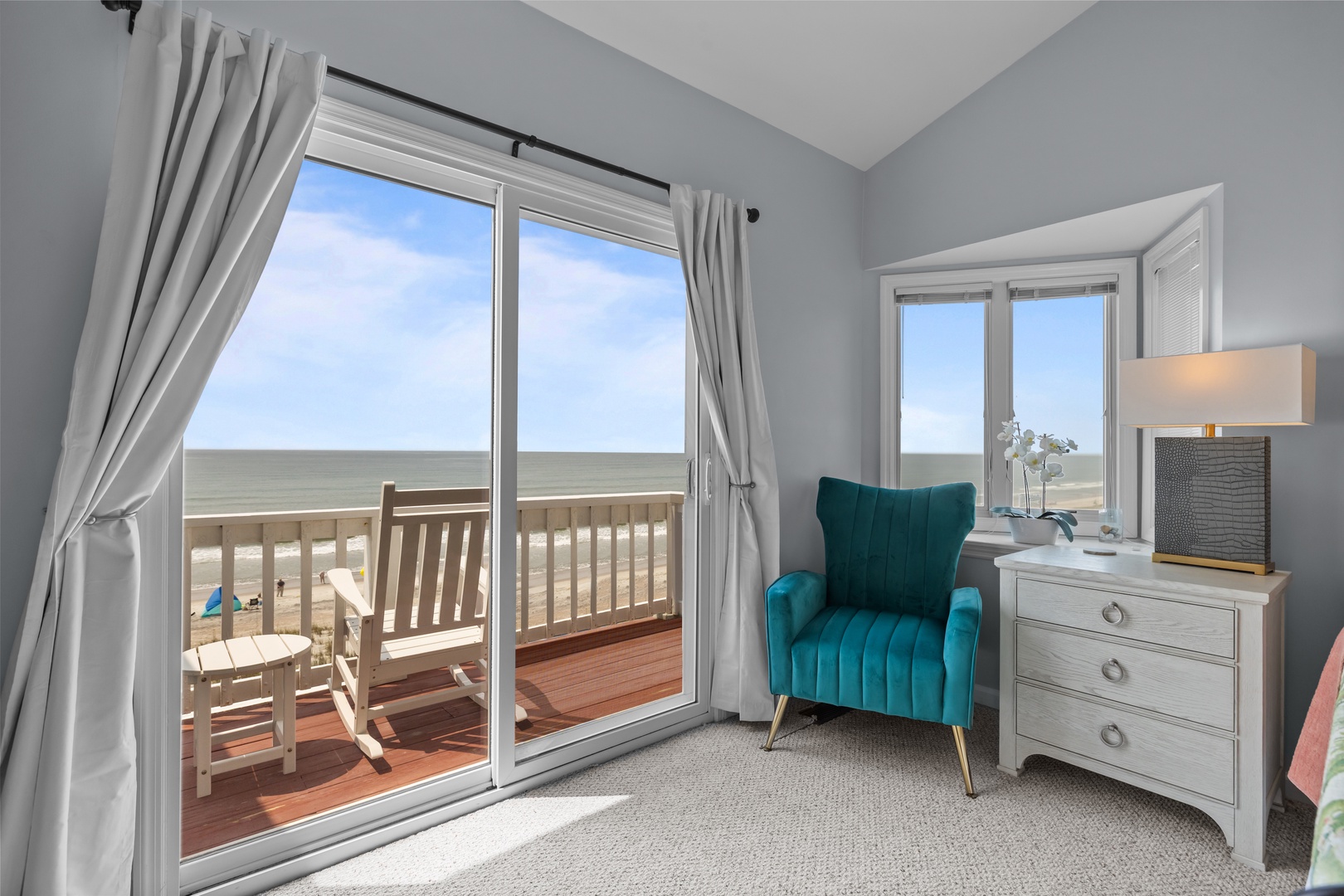 Sink into your teal velvet chair and watch waves roll in through floor-to-ceiling windows opening onto your private deck.