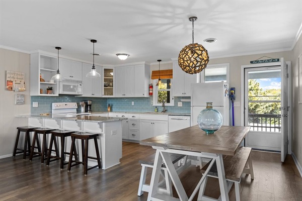 Your spacious kitchen features white cabinets, modern pendant lighting, and a breakfast bar where you can enjoy morning coffee.
