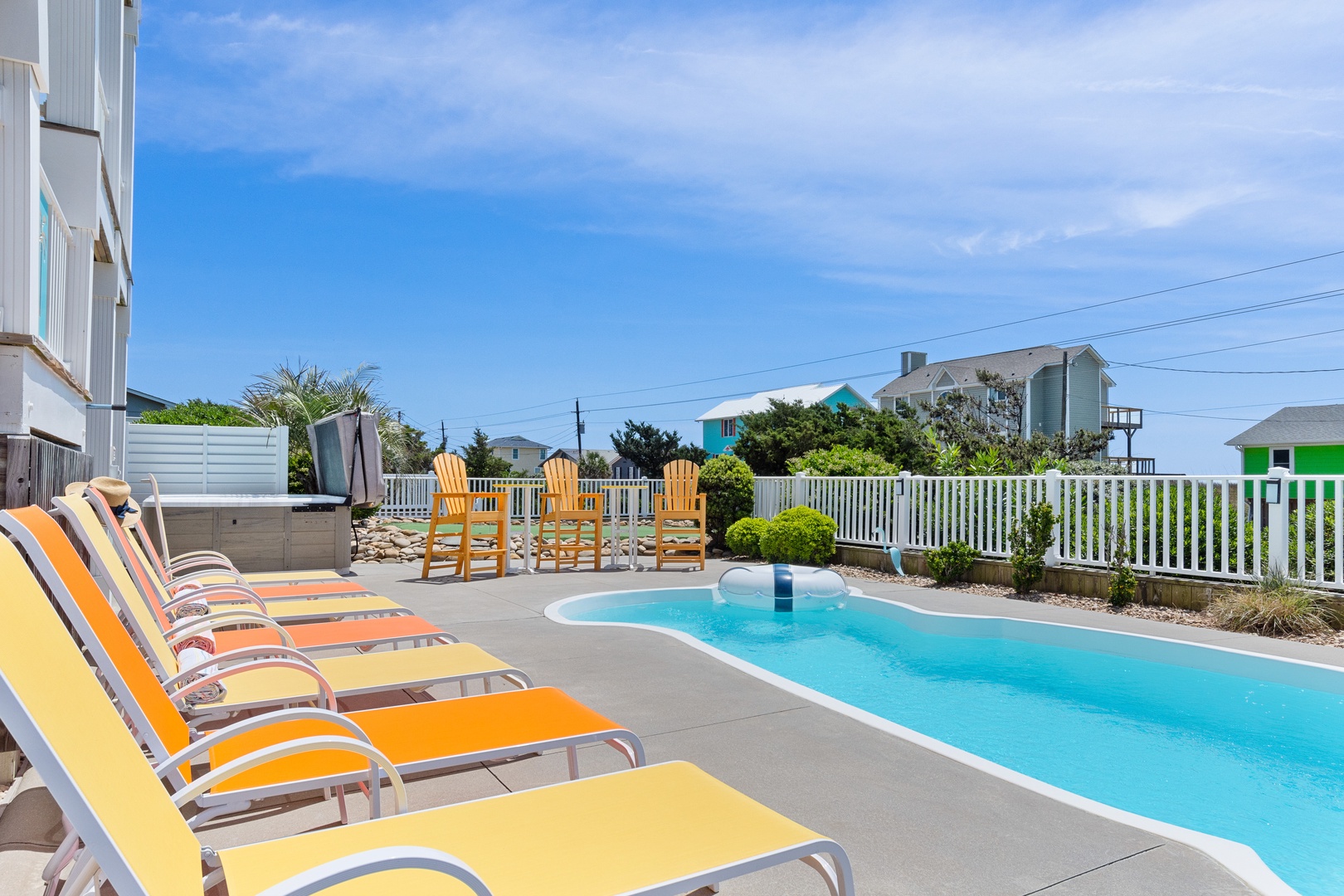 Soak up the sun on colorful lounge chairs beside your private pool, where wooden seating and fenced privacy create perfect summer relaxation.