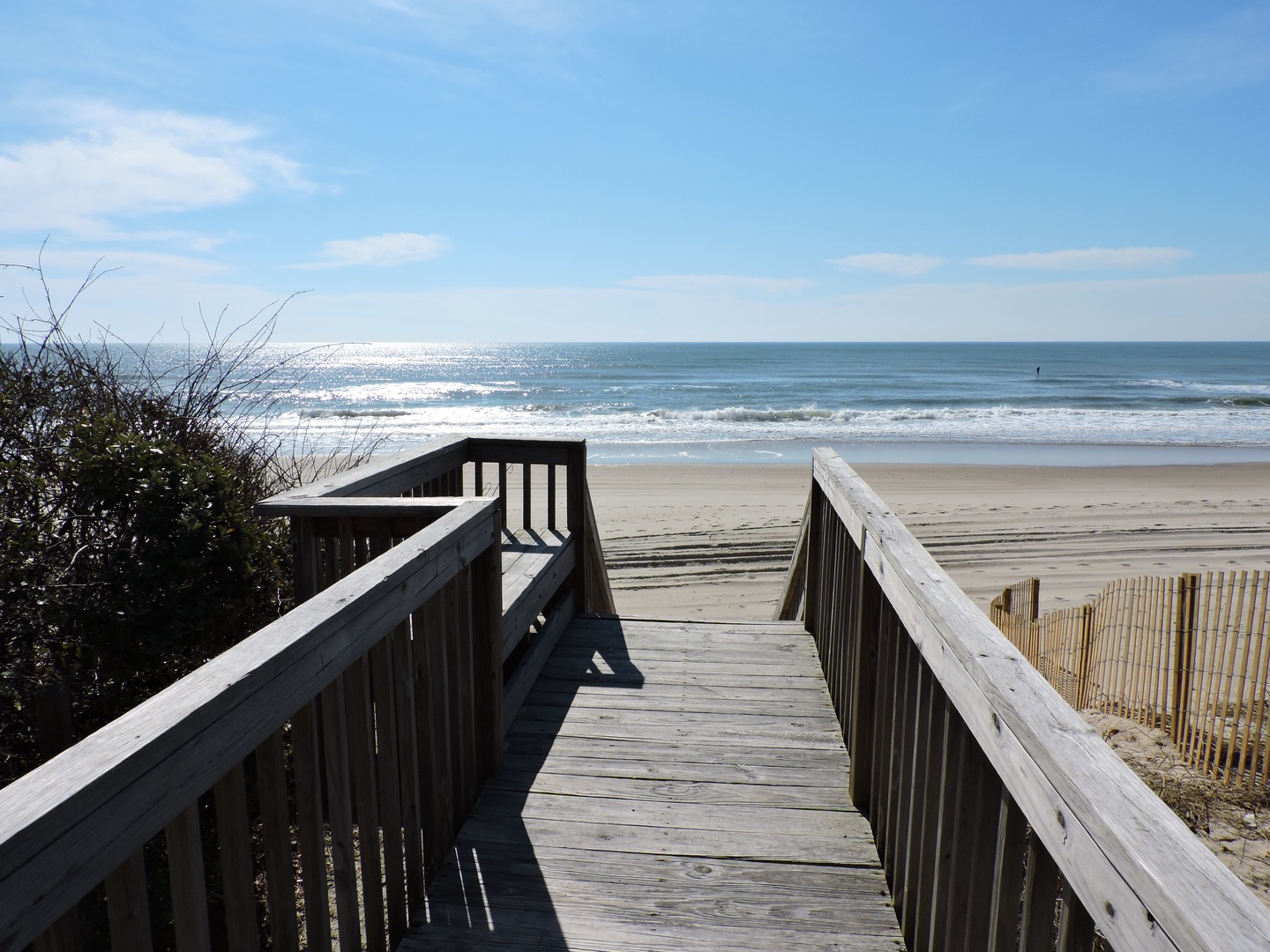 Private beach access walkway leads to pristine sandy shores with rolling waves and endless ocean views.