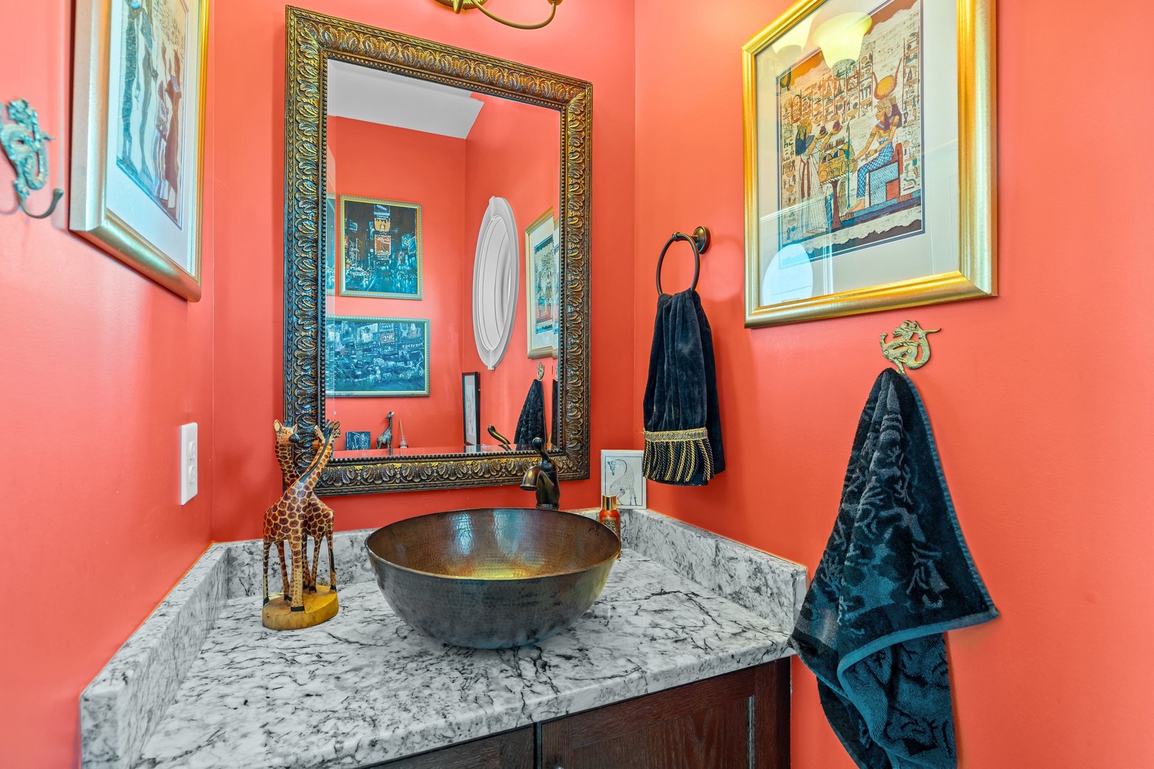 Vibrant coral walls and marble vanity create your perfect powder room retreat, complete with vessel sink and elegant artwork.
