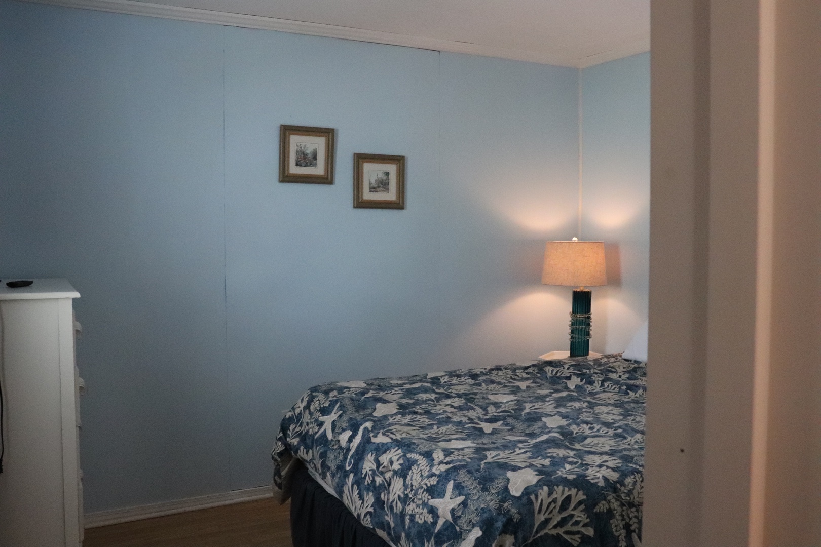 Your peaceful bedroom features soothing coastal blue walls, a comfy bed with ocean-inspired bedding, and gentle lighting for relaxing evenings.