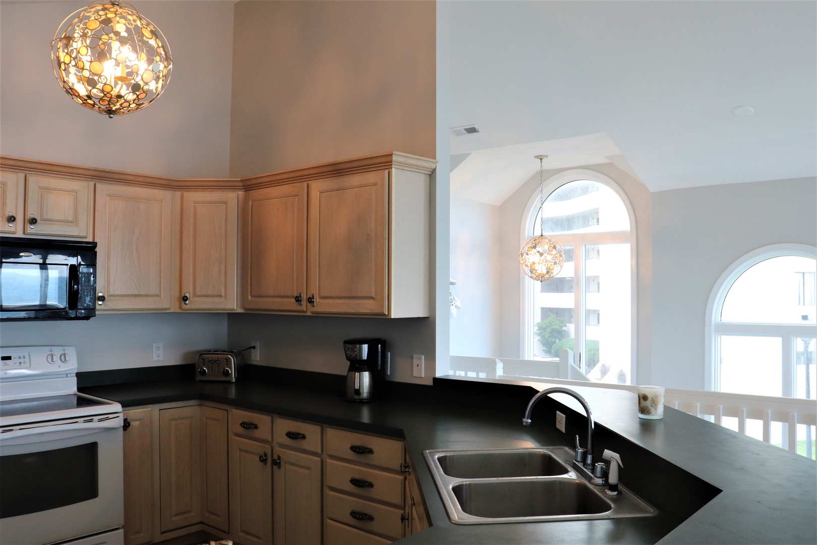Your fully equipped kitchen features warm wood cabinetry, sleek dark countertops, and elegant pendant lighting—perfect for preparing meals together.