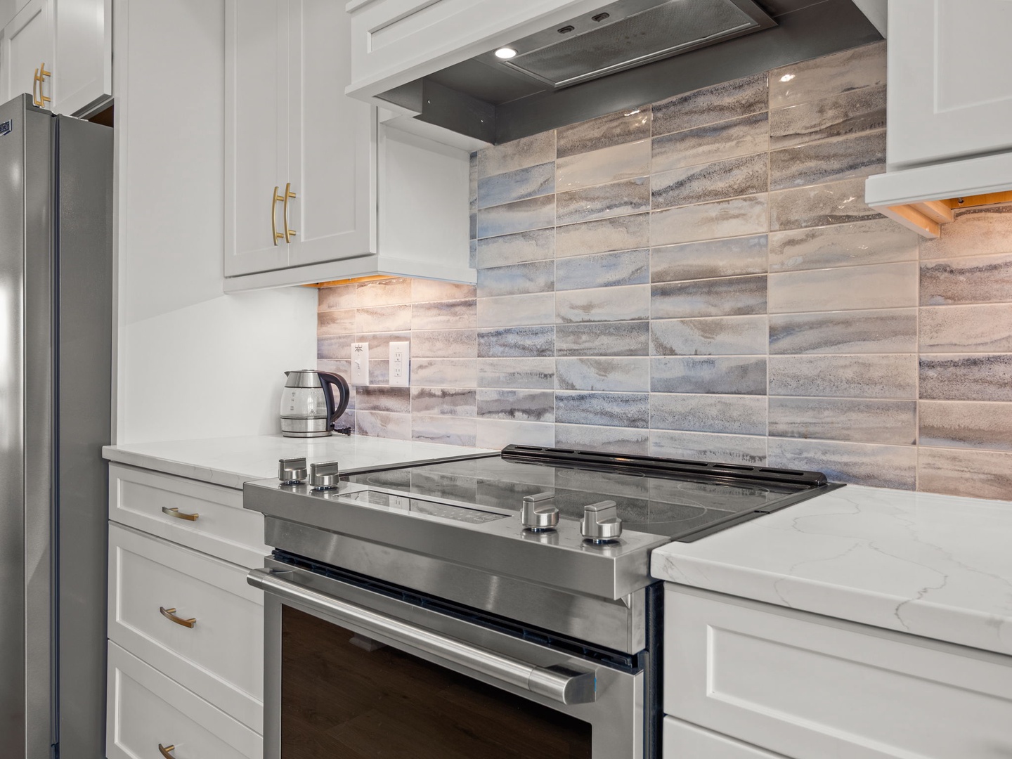 Your modern kitchen features sleek white cabinetry, marble countertops, and a stunning wood-tone backsplash that creates the perfect space for cooking.