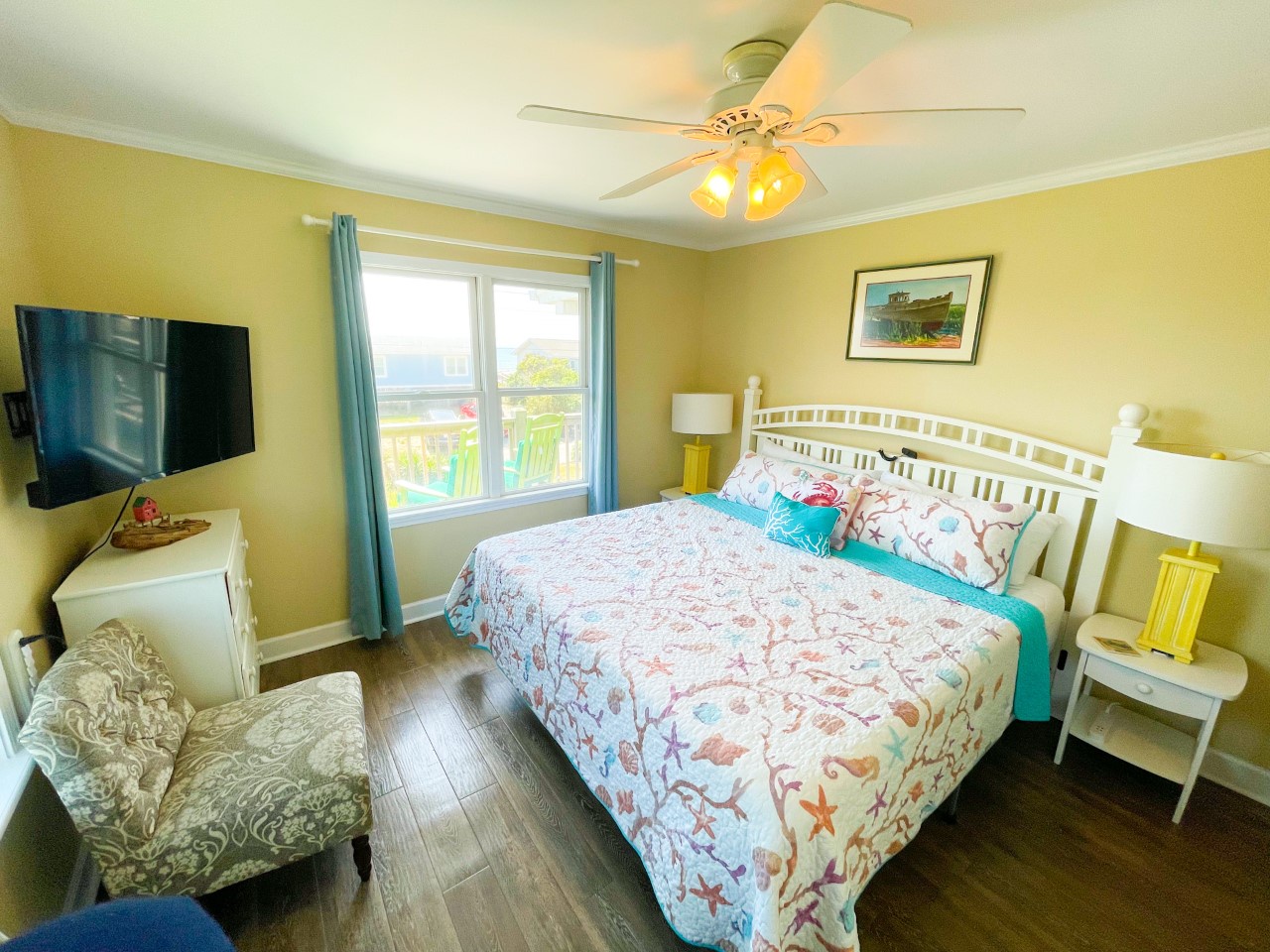 Your bright, cheerful bedroom features a comfortable queen bed with coastal bedding and TV for relaxing evenings after beach adventures.